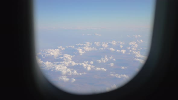 View to the clouds and land from flying airplane