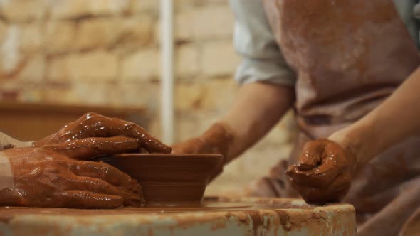 Hands of the Skilled Master Potter and Woman Hands Training of the Woman to Production of Pottery on