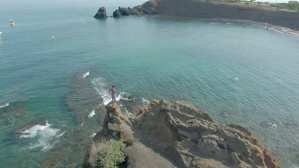 Aerial Shooting of a Young Attractive Man Standing on a Cliff 