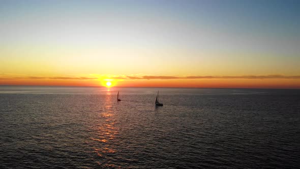 Two Yachts Sail in the Sea at Sunset