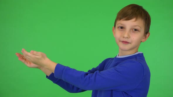 A Young Cute Boy Presents Something To the Camera with a Smile - Green Screen Studio