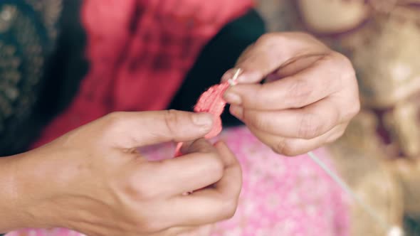 Close up of old woman's hands knitting with needle crafts and red wool. Close up of knit work tie-up