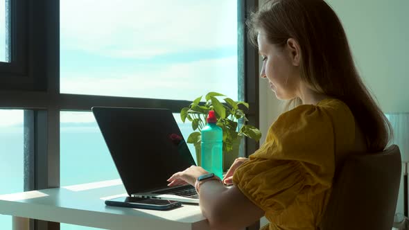 Young Female Using Laptop Communicates on Internet with Customer in Home