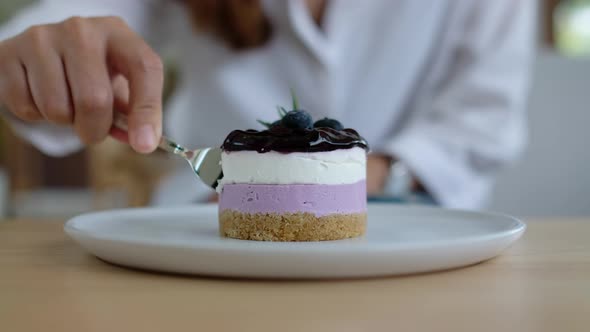 Closeup of a woman eating a piece of blueberry cheesecake