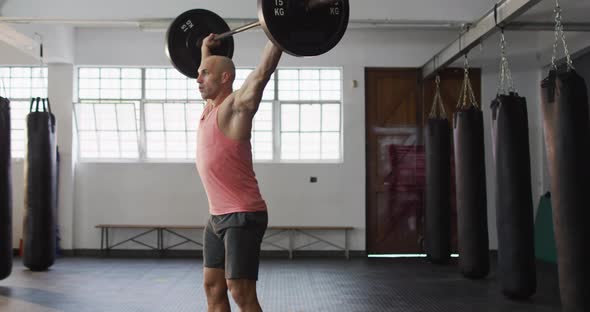 Caucasian male trainer working out with barbell at the gym