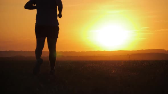 Running Man Silhouette in Sunset Time. Outdoor Cross-country Running. Athletic Young Man Is Running