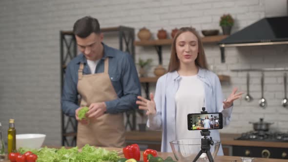 Young couple cooking together and recording video food blog on camera in the kitchen at home