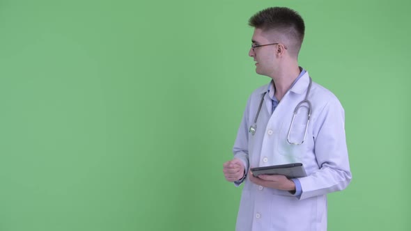 Happy Young Man Doctor Presenting While Showing Digital Tablet