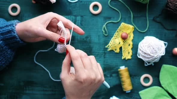 Woman knitting using hooks and white yarn