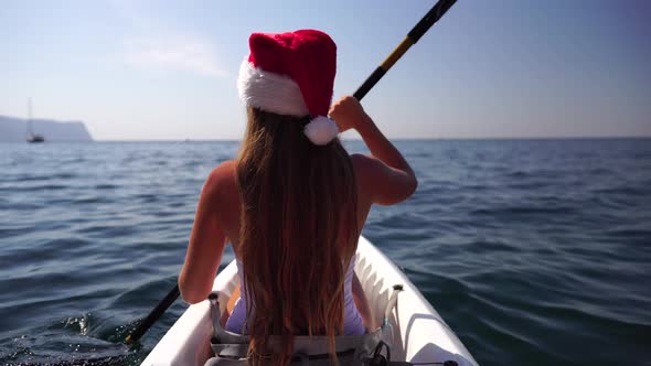 Young Attractive Brunette Woman with Long Hair in White Swimsuit Swimming on Kayak Around Volcanic