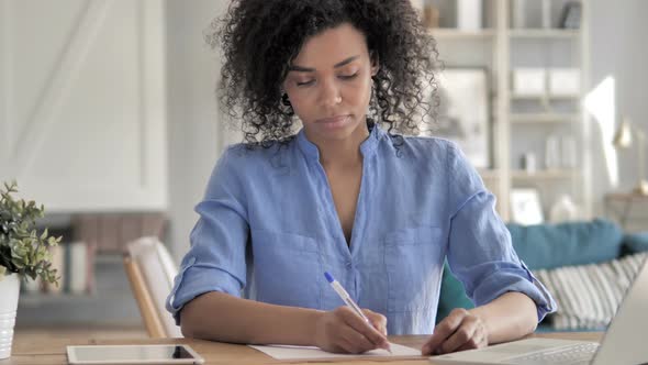 African Woman Writing on Paper at Work