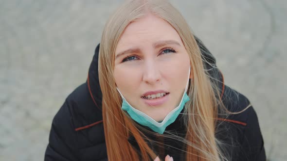 Crane Shot of Blonde Woman Looking Into the Sky and Putting on Medical Mask