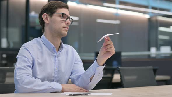 Young Man Holding Paper Plane in Office