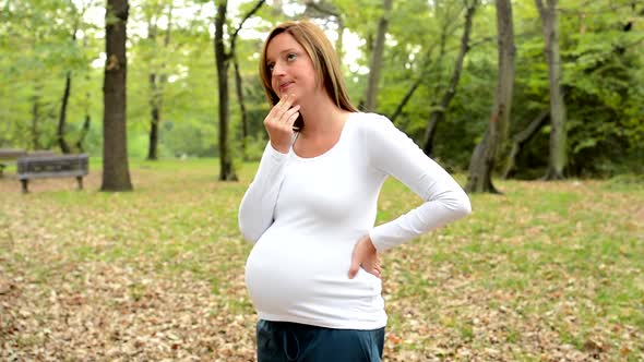 Young Pretty Pregnant Woman Think About Something in Park