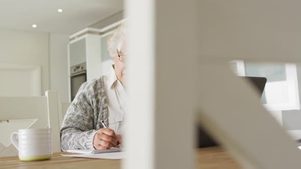 African american senior woman with laptop taking notes at home