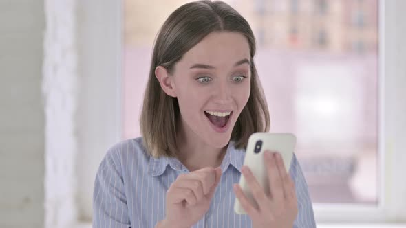 Portrait of Ambitious Young Woman Celebrating on Smartphone