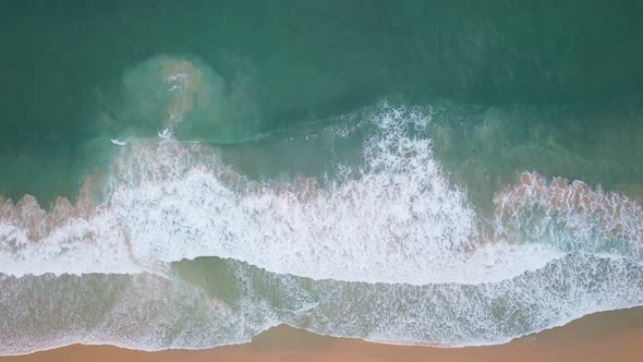 Top View of the sea surface Waves crashing on beach sand