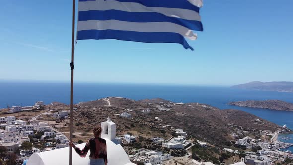 Aerial view from the top of Ios island in Greece, woman and greek flag