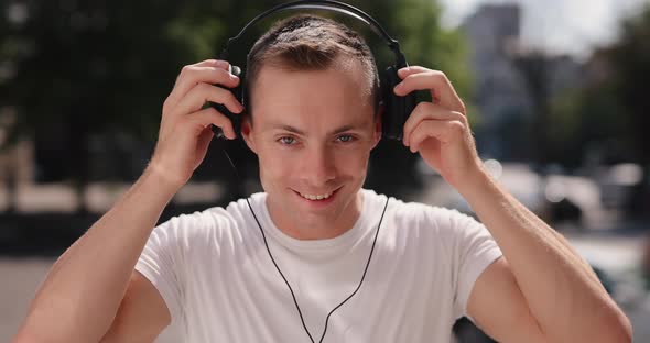 Smiling Man Wearing Big Headphones in the Summer City