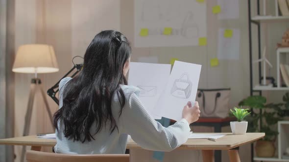 Back View Of Asian Woman Designer Looking At Hand Bag Sketching On The Layout Bond In Hand