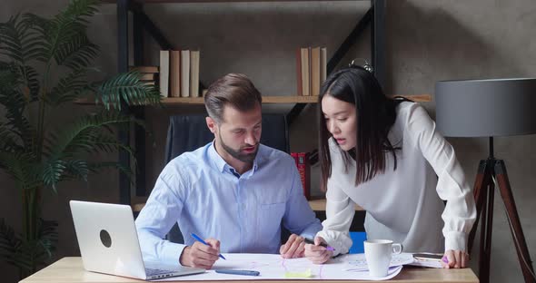 A Businessman and Asian Businesswoman Engineers Working in Loft Style Office