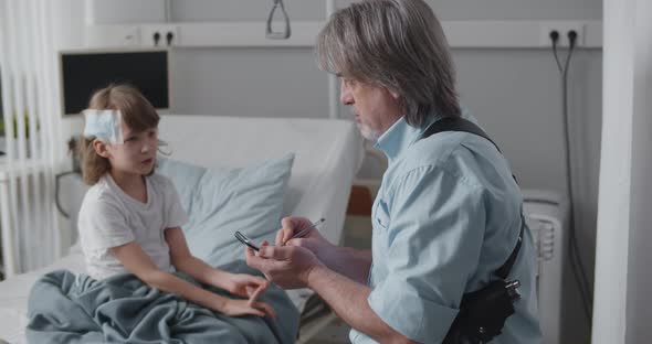 Aged Policeman Questioning Little Kid in Hospital Investigating Accident