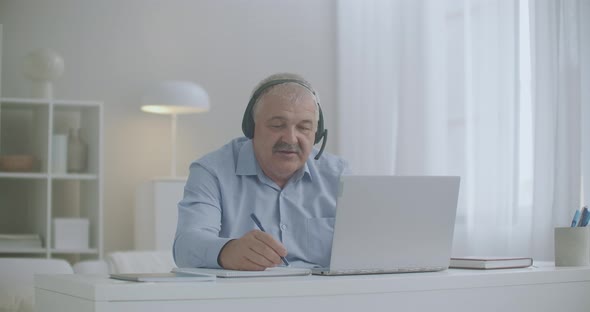 Middle-aged Man Is Communicating By Online Chat with Colleagues and Employees From Home Using Laptop