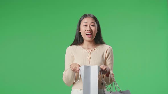 Asian Shopping Woman Being Happy After Opening Shopping Bag While Standing In Front Of Green Screen