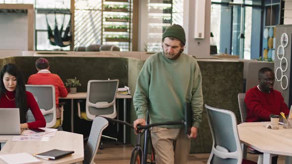 Young Businessman with Bicycle Walking into Office