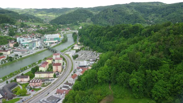 Flying toward railroad bridge over river with beer brewing factory at the other side. Aerial 4k view