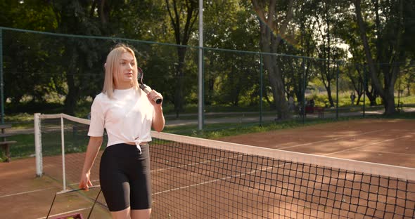 Woman with Box of Tennis Balls Walking on Court