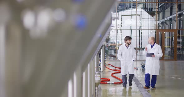 Two Caucasian Men Walks at a Brewery Factory