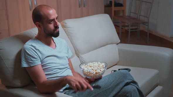 Caucasian Male Chilling on Sofa with Popcorn Bowl in Hands While Watching Movie Series