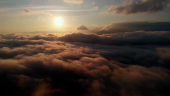 Aerial view: Flying Over Clouds on Sun Rise in Mountains.