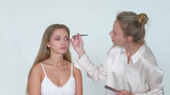 Young Makeup Artist Doing Makeover To Pretty Model