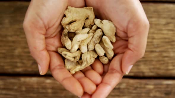 Hands holding dried ginger against wooden table 4k