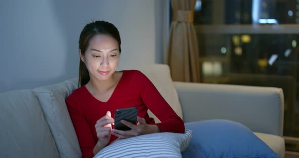 Woman use of mobile phone at home in the evening