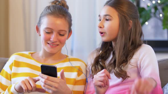 Happy Girls with Smartphone and Earphones at Home