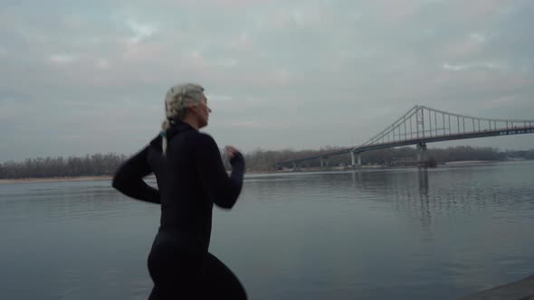 Sportswoman Running Near River in Evening