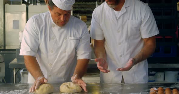 Chefs kneading pizza dough on the floured table