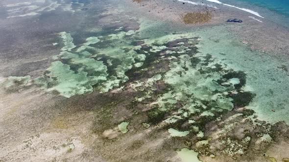 Aerial drone rising over crystal clear water at low tide on a remote, idyllic tropical island destin