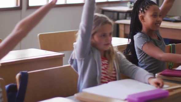 Group of kids raising their hands in the class at school