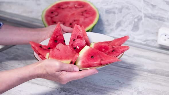 Female Hands Holding Plate with Ripe Watermelon Triangle Slices on White Plate