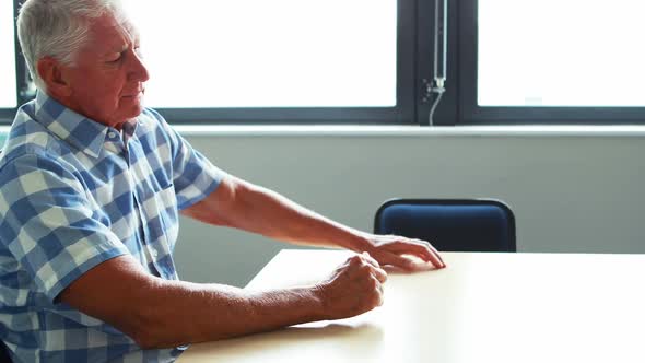 A senior man sitting at table thinking