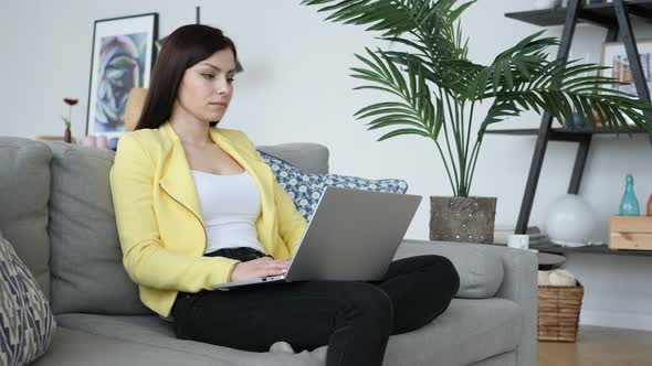 Young Woman Working On Laptop, Sitting on Sofa in Office