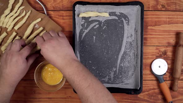 Putting the wrapped sticks on the baking sheet to bake in the oven.