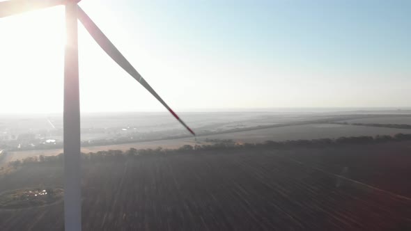 Cinematic 4K sweep aerial panorama of wind turbines power plant rotor backlight in sunrise sun