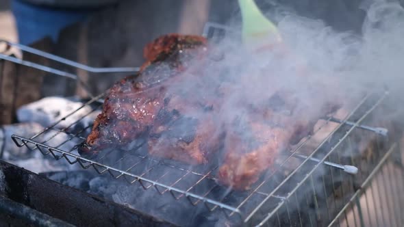 Delicious Beef or Pork Ribs Frying on a Charcoal Grill Being Covered with Red Gravy Sauce Brush