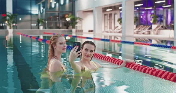 Young Females in the Swimming Pool Two Beautiful Girls in Yellow Swimsuits Take a Selfie on a