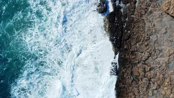 Sea Washes the Rocky Shore Above Aerial Shot Flying Over Coastline Cliffside with Blue Pure Water